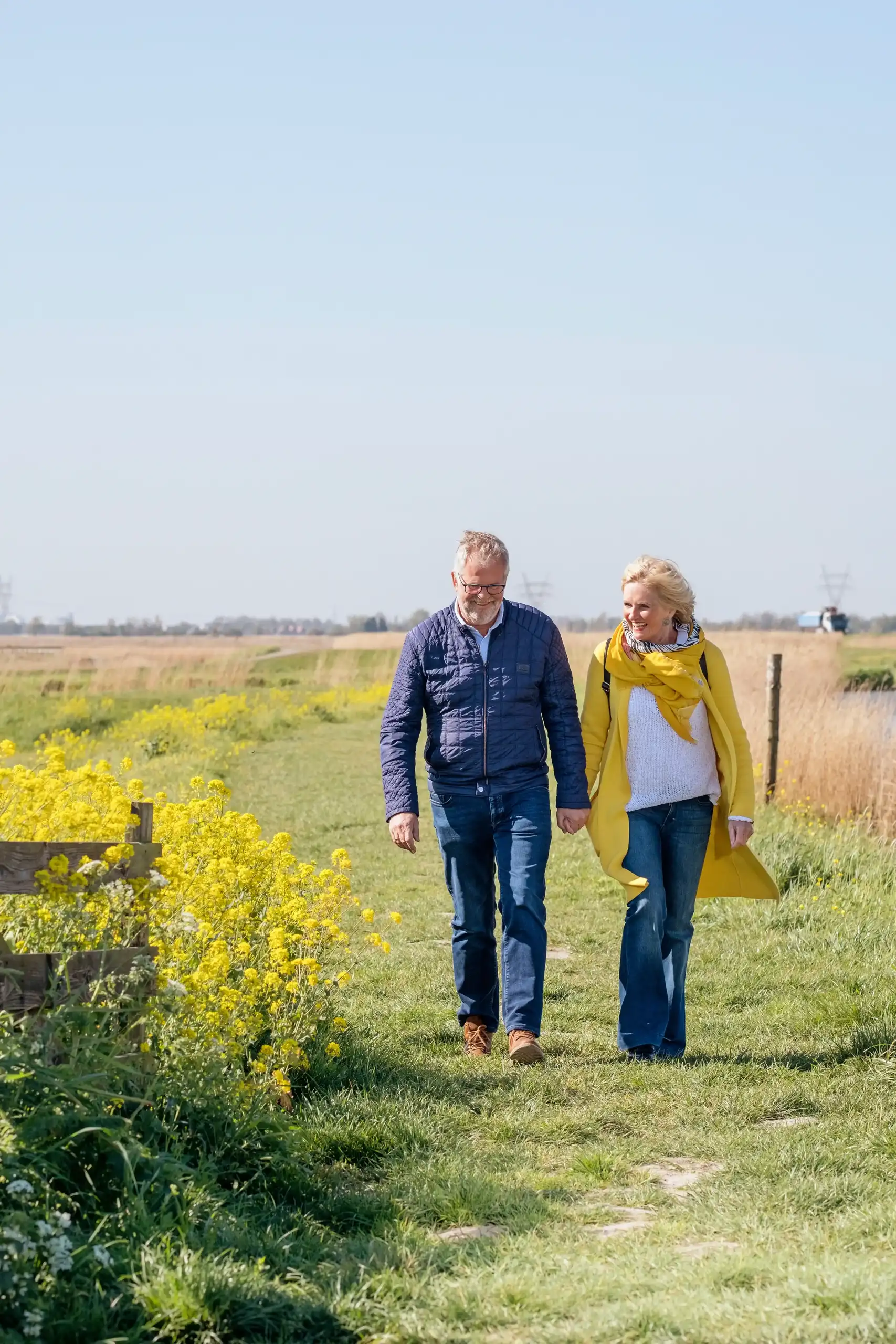Man en vrouw hand in hand aan het wandelen door de polder